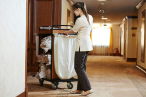 chambermaid pushing bedsheet cart