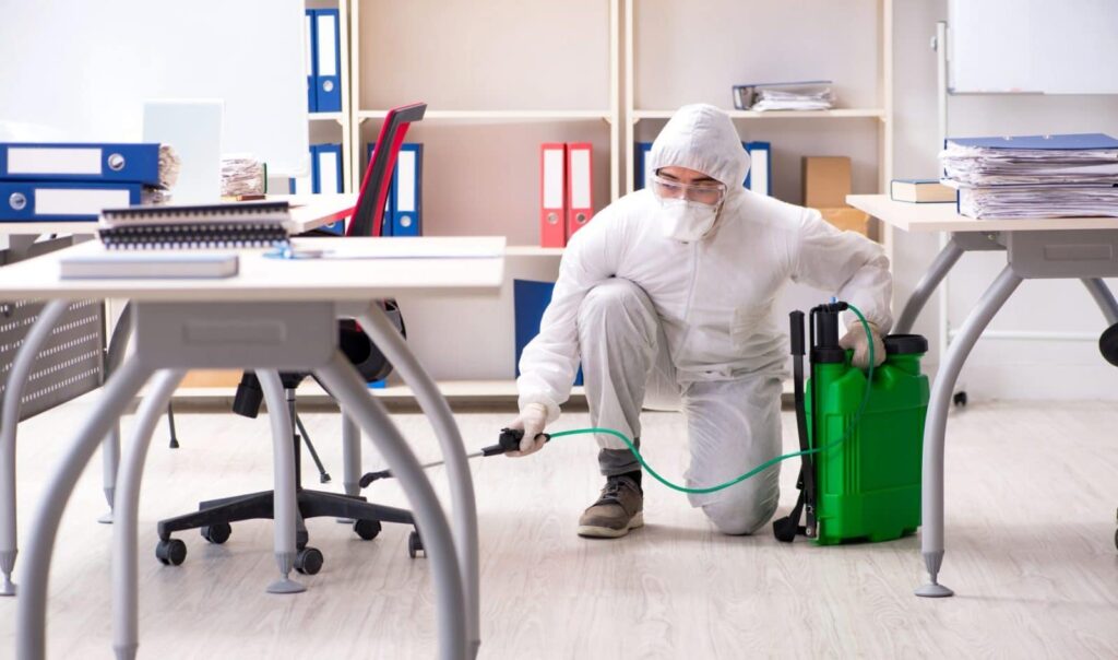 man disinfecting under the office table