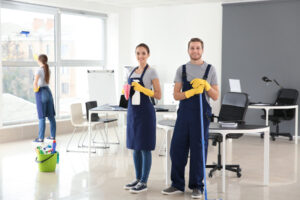 happy cleaning crew smiling while the other one cleans the window