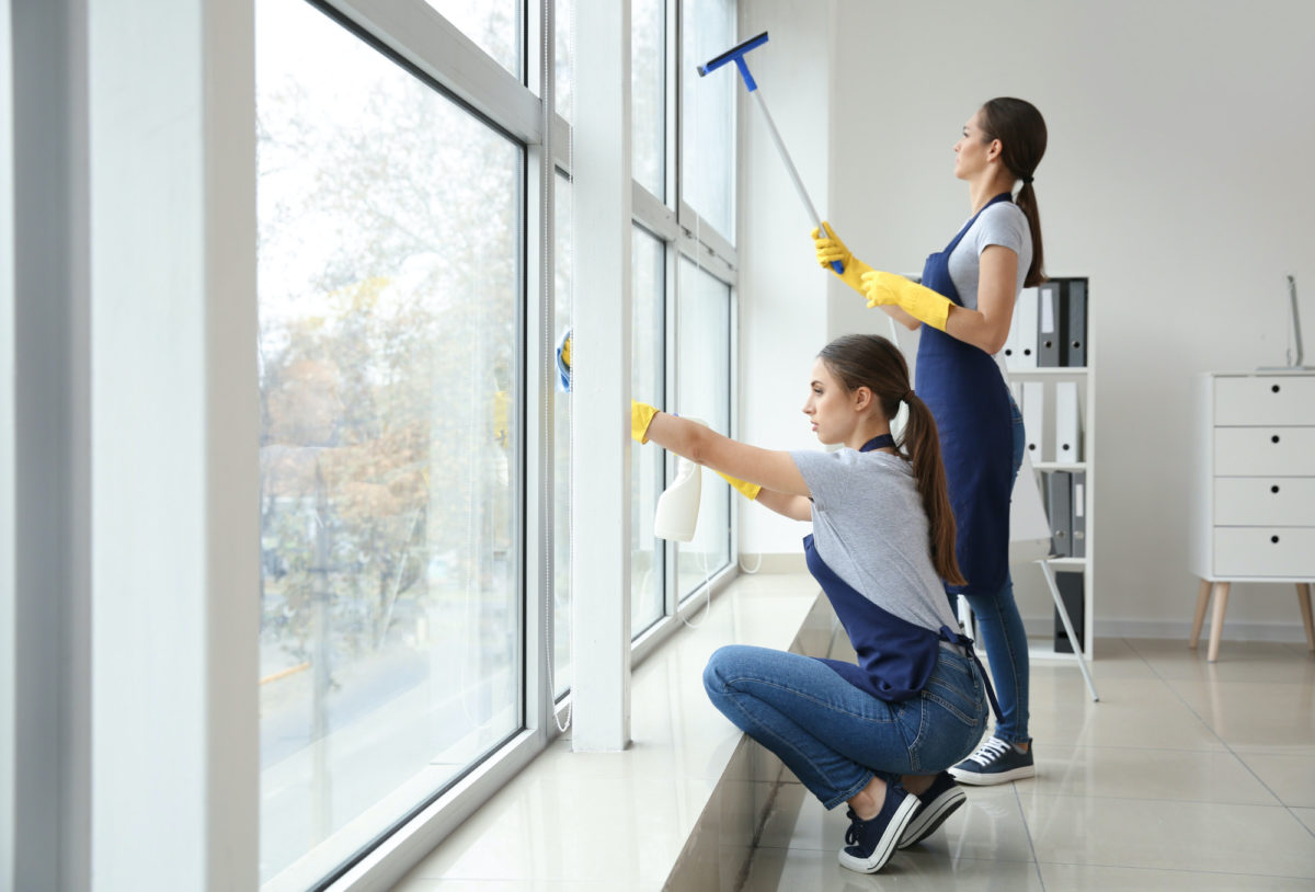 two woman cleaning the window inside