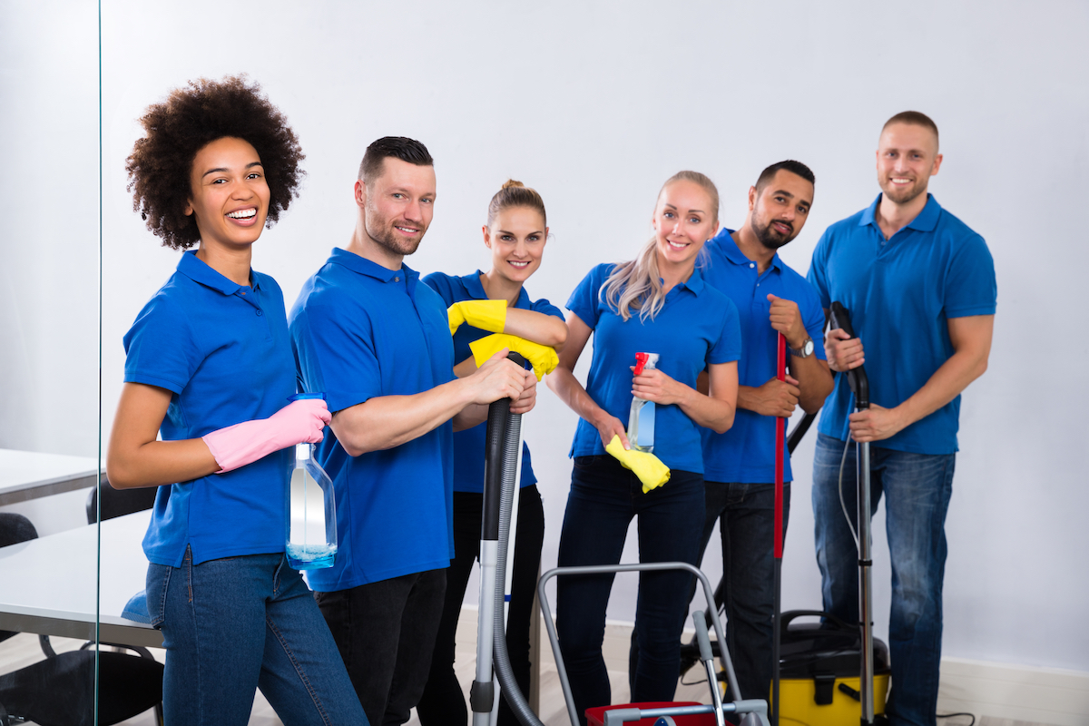 cleaning crew happily pose with their cleaning equipments