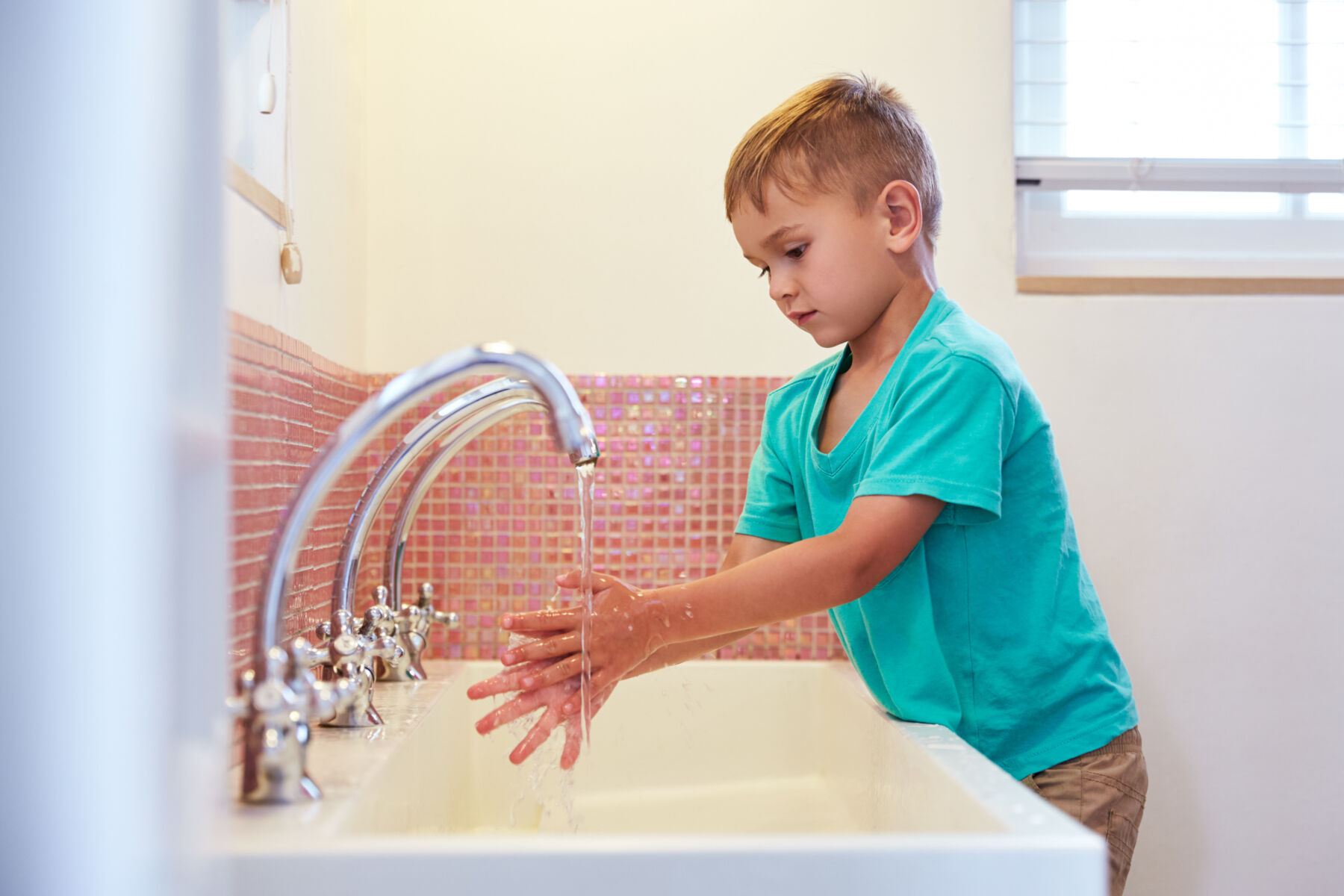 Image emphasizing a kid washing hands, relevant to cleanliness in school bathrooms