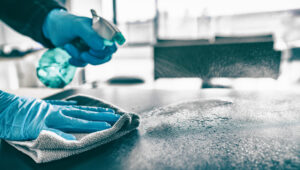 janitor low-level disinfecting a conference table in a dallas business with gloves and disinfectant