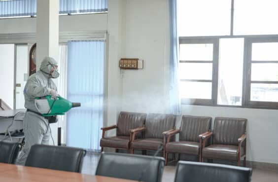 Disinfecting of Fort Worth office to prevent contagions, person in white PPE with sanitizing waiting room chairs in Fort Worth clinic