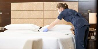 hotel cleaner arranging bedroom pillows