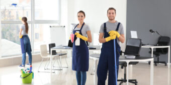 happy cleaning crew smiling while the other one cleans the window