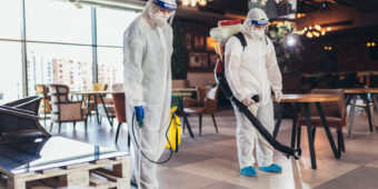 professional cleaners in hazmat suits, disinfecting a commercial place