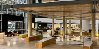 A clean and well-maintained modern office atrium lobby with glass walls and seating areas in a commercial building in Dallas.