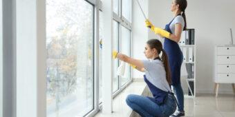 two woman cleaning the window inside