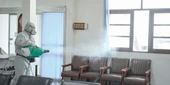 sanitizing waiting room chairs in Fort Worth clinic Disinfecting of Fort Worth office to prevent contagions, person in white PPE with sanitizing waiting room chairs in Fort Worth clinic