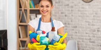 pretty young cleaner smiling while holding the cleaning materials