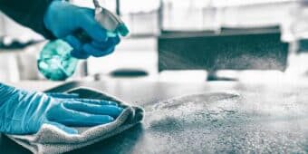 Low Level Disinfection Dallas Office janitor low-level disinfecting a conference table in a dallas business with gloves and disinfectant