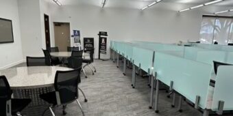 Modern office training room with workstations, tables, and carpeted floors.