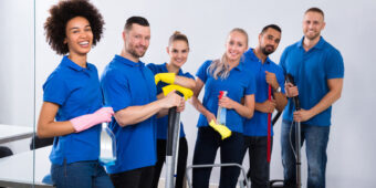 cleaning crew happily pose with their cleaning equipments